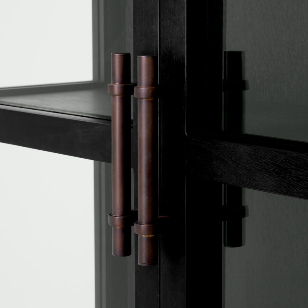 Close-up of a black cabinet with a bronze handle on a neutral background