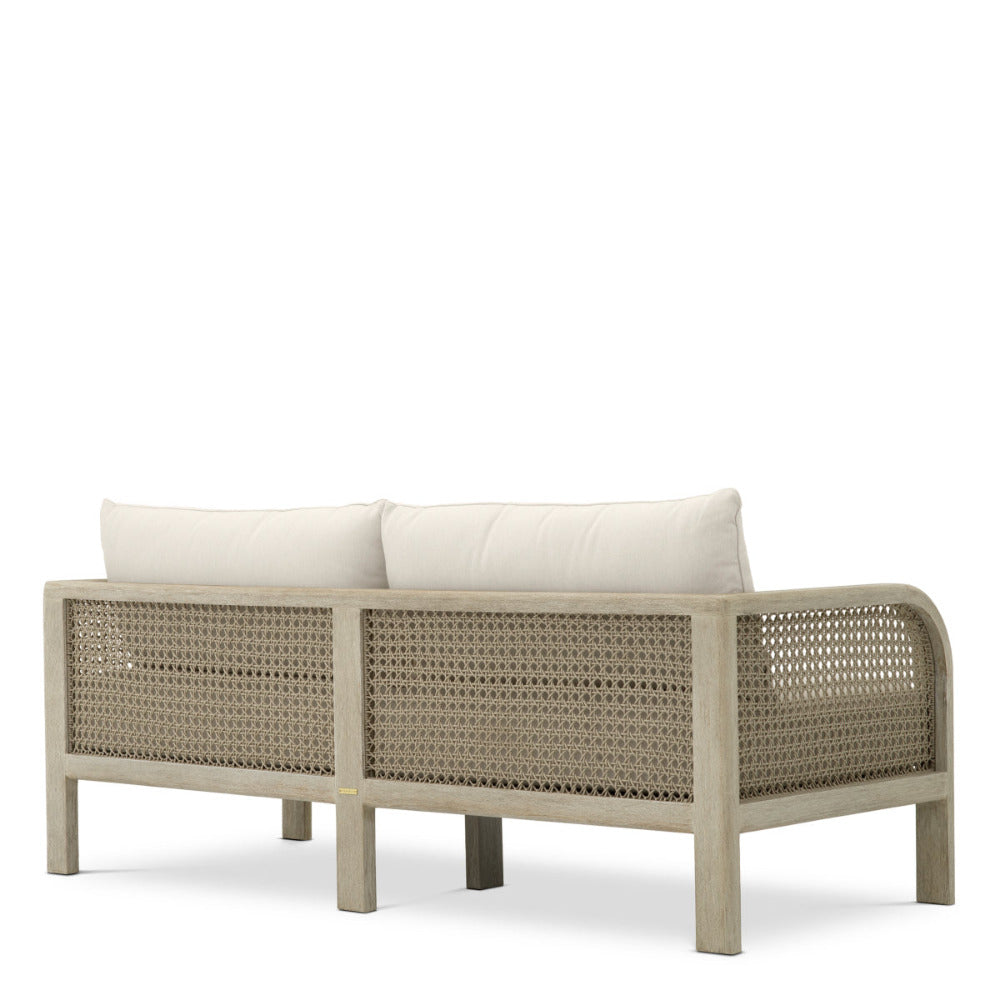 Wicker outdoor sofa with white cushions on a white background
