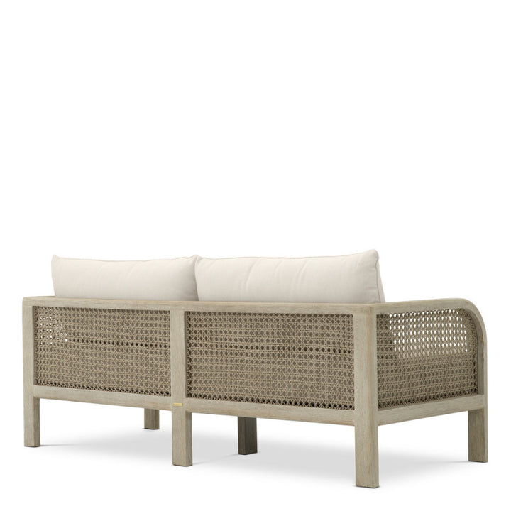 Wicker outdoor sofa with white cushions on a white background