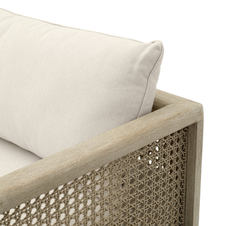 Close-up of a sofa with woven armrest and beige cushion on a white background