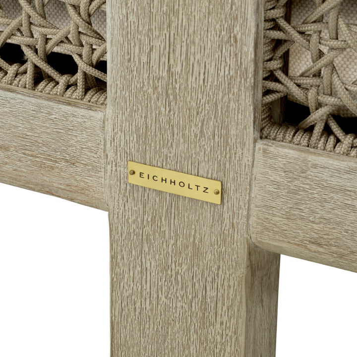 Wooden side table with woven design and Eichholtz label on a white background