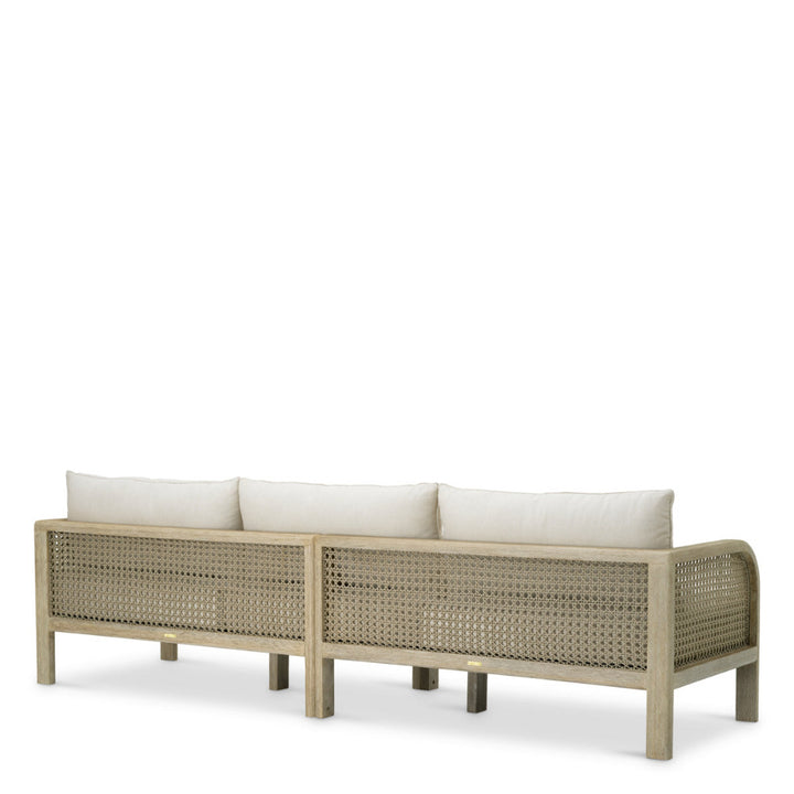 Beige outdoor sofa with wicker design and white cushions on a white background