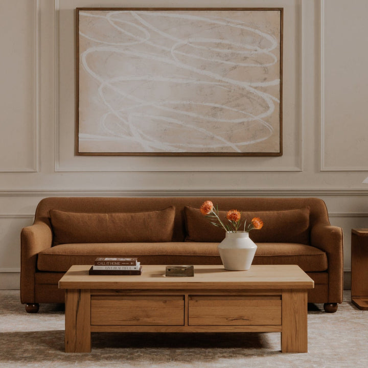 Living room with brown sofa, beige armchair, wooden coffee table, and abstract painting on wall.