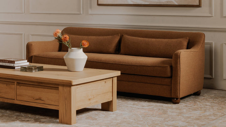 Brown sofa with a wooden coffee table and decorative items in a living room setting.