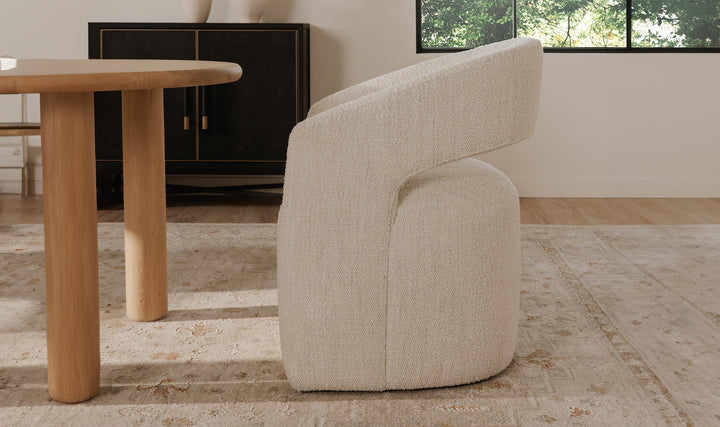 White armchair in a room with a wooden table and a window in the background