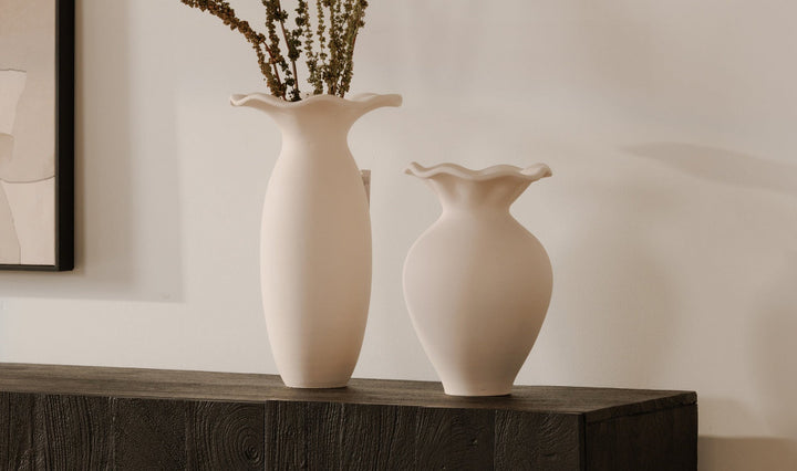 Two white ceramic vases on a wooden sideboard with a neutral background