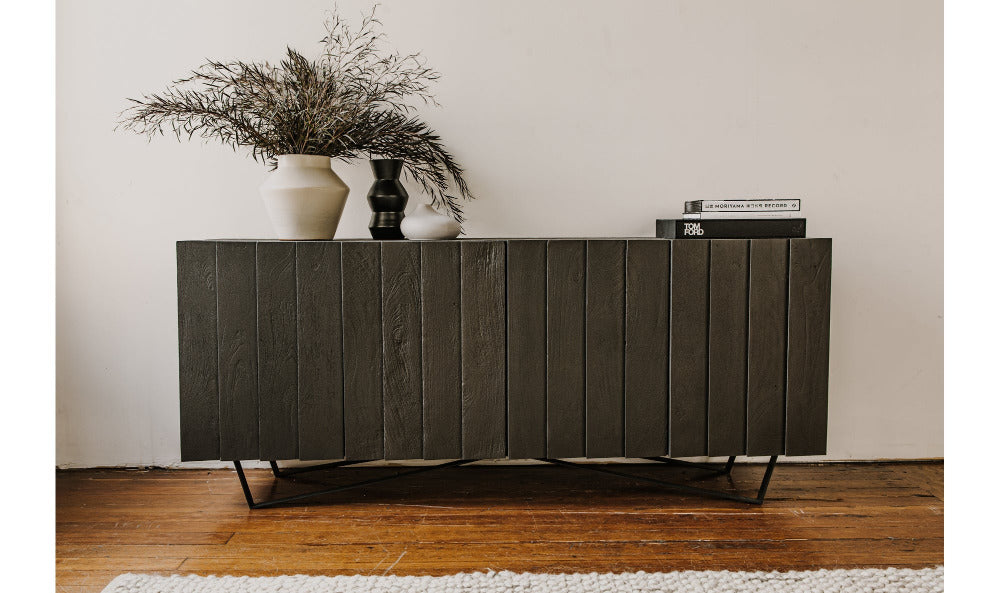 Dark wooden sideboard with decorative items against a white wall