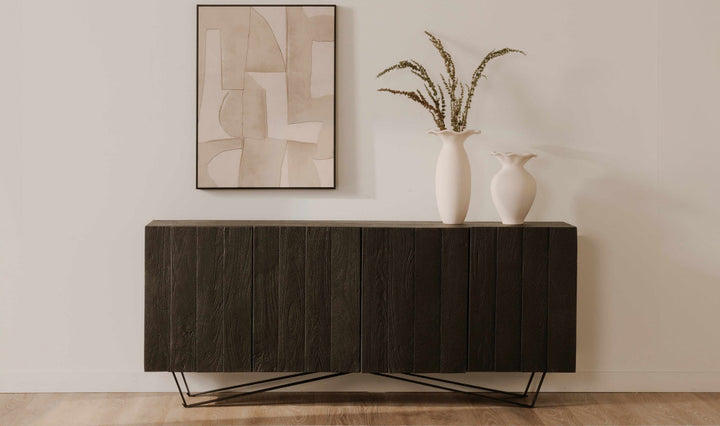 Modern dark wood sideboard table with white vases and abstract art in a minimalistic room.