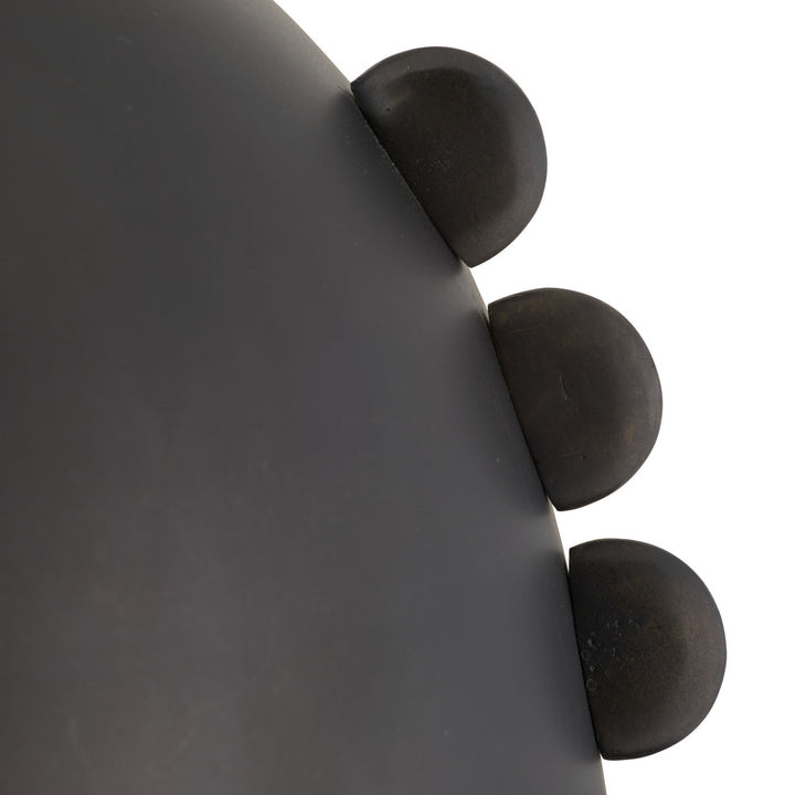 Close-up of a dark gray pendant with three spherical protrusions.