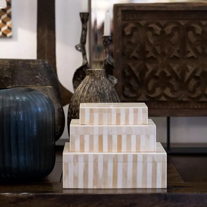 Stack of decorative boxes with striped pattern on a wooden surface