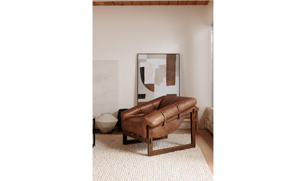Brown leather sofa in a room with abstract art on the wall.