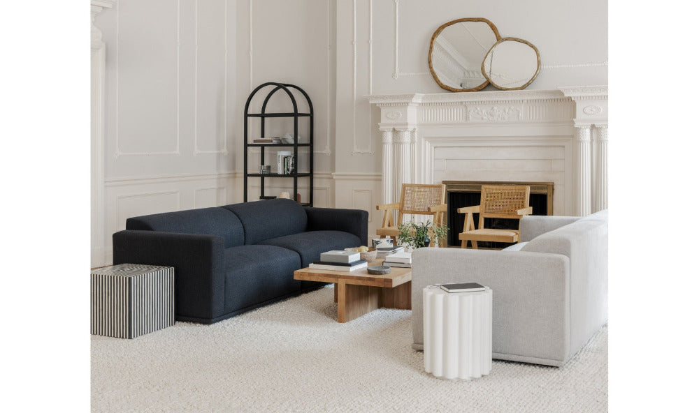 Modern living room with a navy sofa, white armchair, and decorative items.