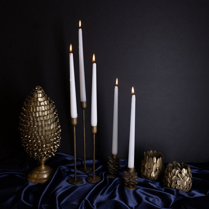 White candles on gold candlesticks with decorative metal tree on a dark background