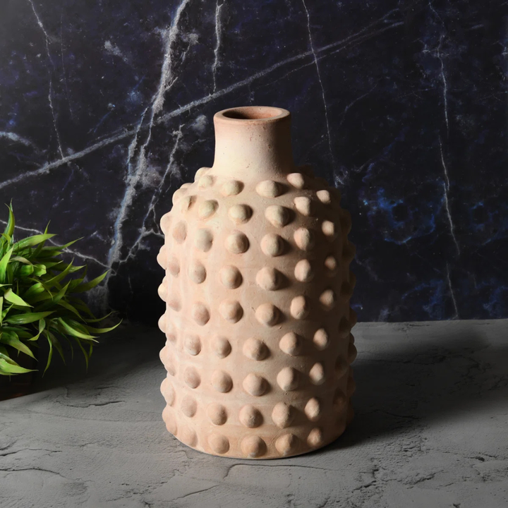 Textured ceramic vase on a dark surface with a marble background