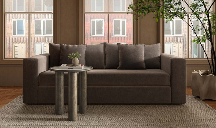 Gray sofa in a living room with a small round table and plants.