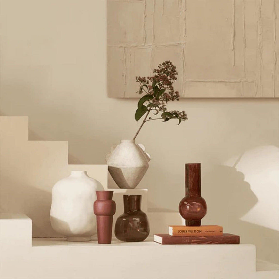 Collection of vases and a book on a surface with a neutral background