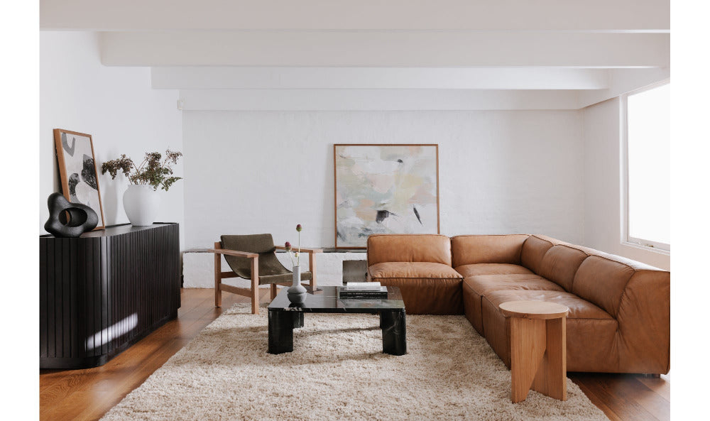 Modern living room with a brown sectional sofa, coffee table, and abstract art on the wall.