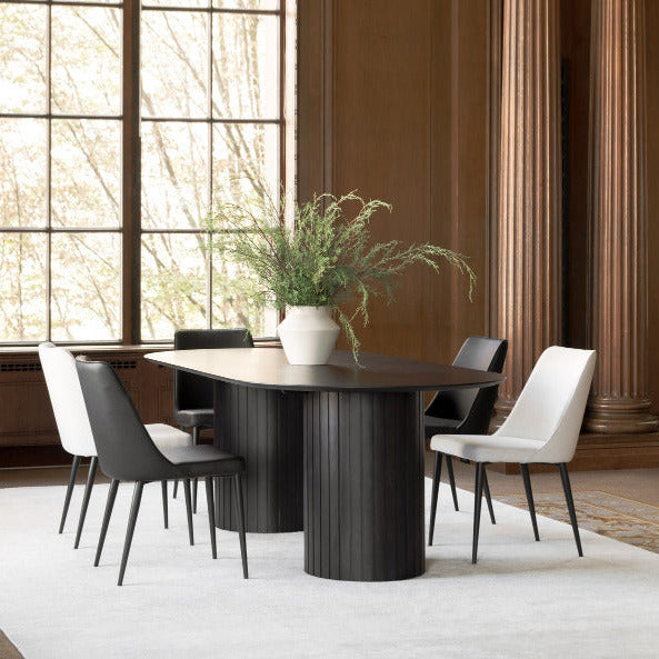 Modern dining room with a round black table and white chairs, large windows, and decorative columns.