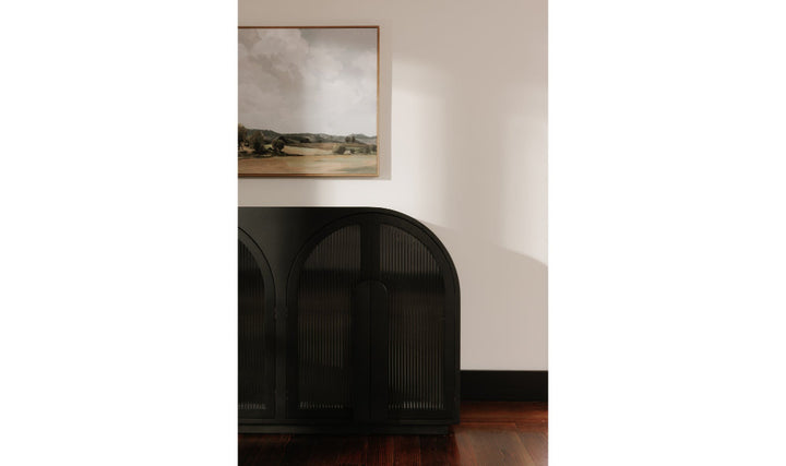 Black sideboard with a landscape painting above it on a white wall.