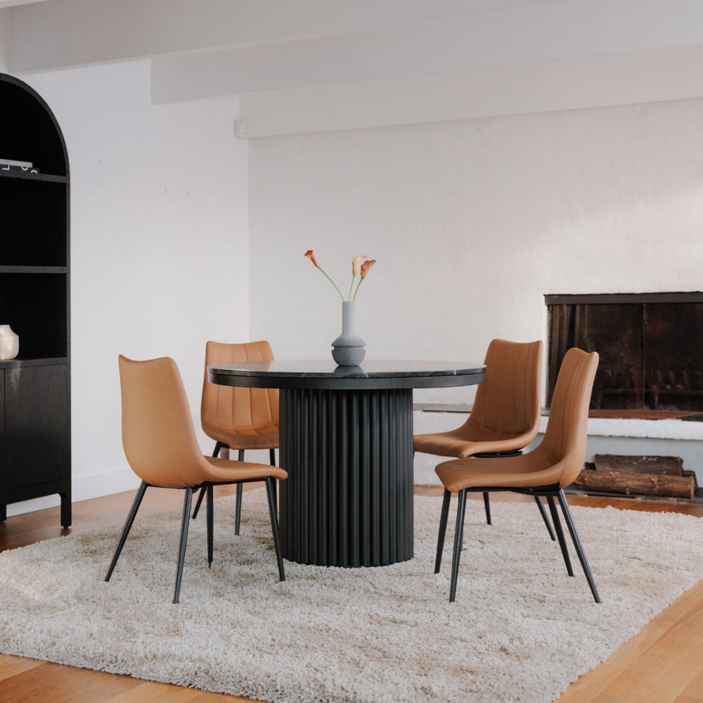 Modern dining room with black round table and brown chairs on a light rug.
