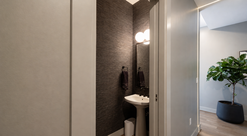 Powder room with textured charcoal wallcovering and a pedestal sink
