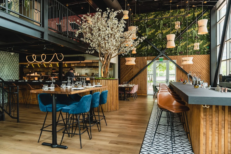 Restaurant dining room with blue velvet counter stools, fluted wood millwork and blossom trees