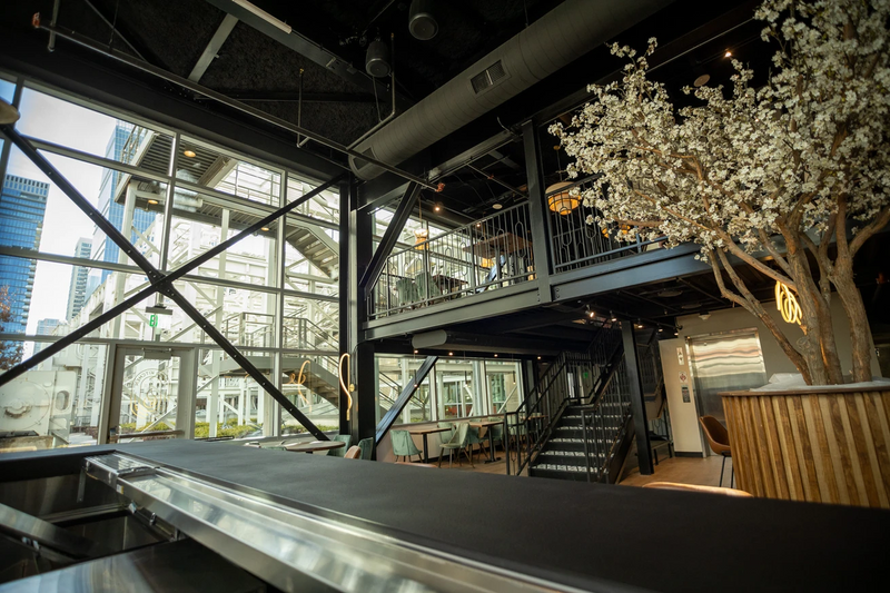 Two-story downtown Houston restaurant with exposed steel structure and a blossom tree