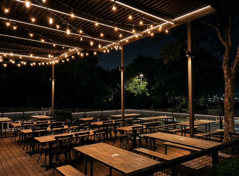 Covered restaurant patio with string lights, communal tables and a timber pergola at dusk