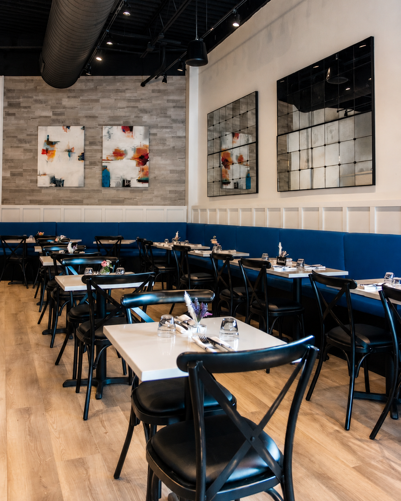 Restaurant dining room with navy banquettes, gallery-hung artwork and bentwood chairs