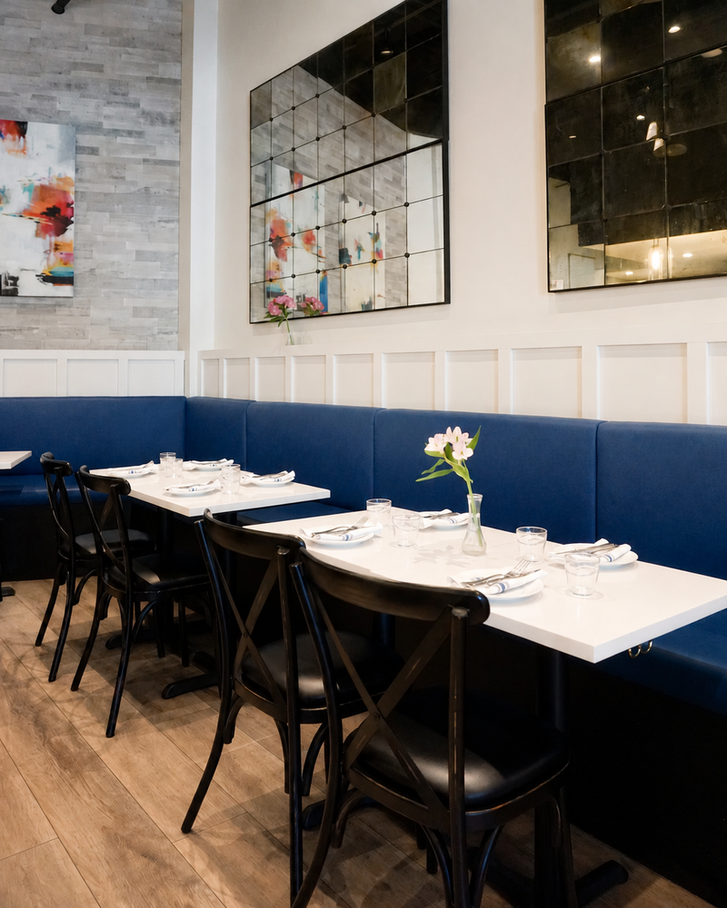 Restaurant with a navy leather banquette, board-and-batten wainscot and bistro tables