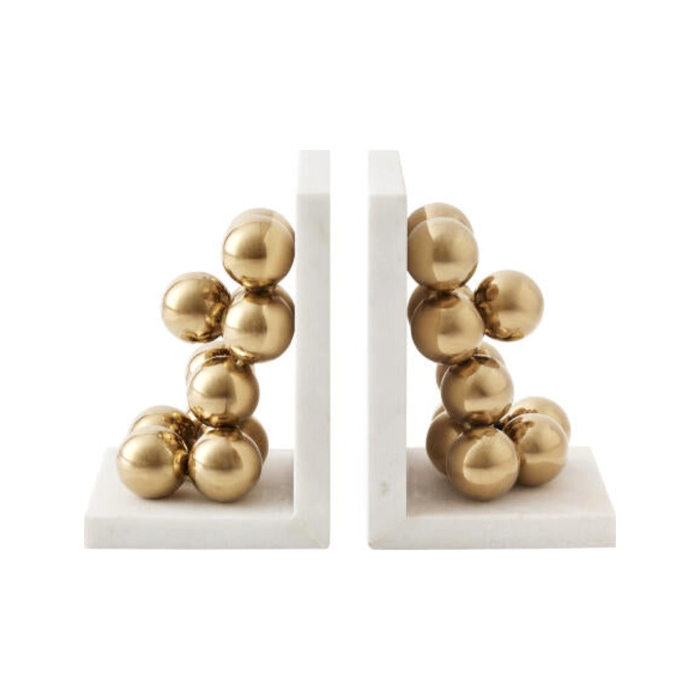 Brass stacked sphere bookends on white marble bases, white background
