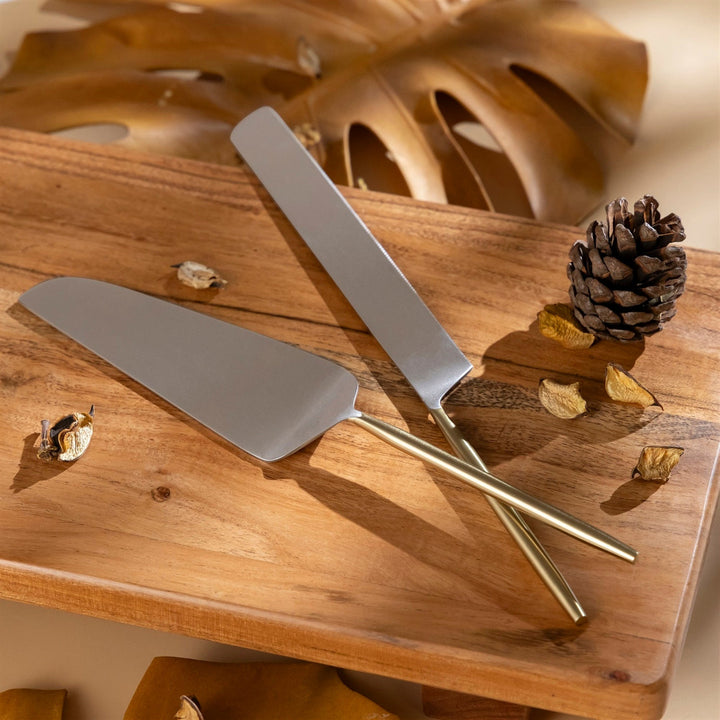 A cake knife and server on a wooden surface with decorative elements.