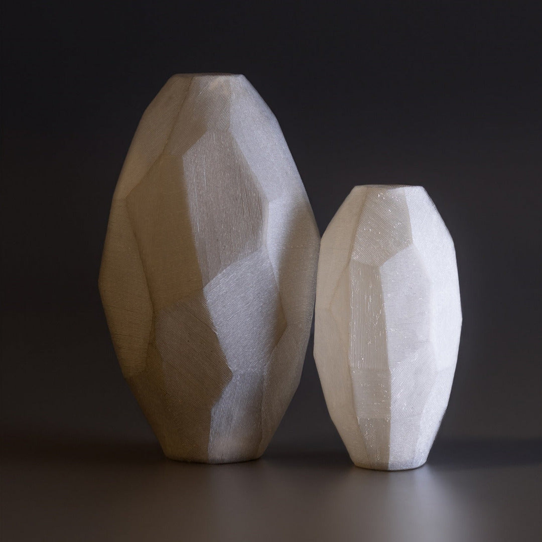 Two glass vases with a faceted design on a dark background