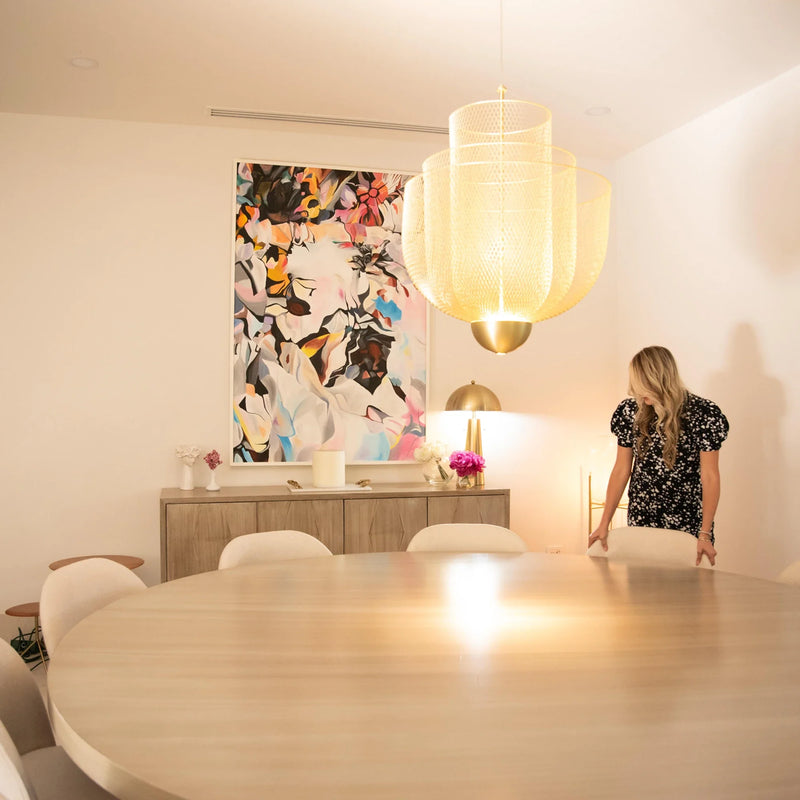 Dining room with an oversized abstract painting, oak sideboard and woven brass pendant