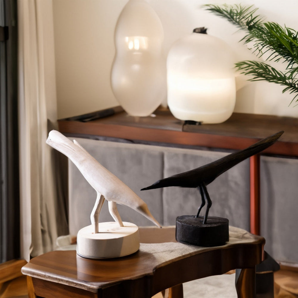 Decorative bird sculptures on a wooden table with a blurred background